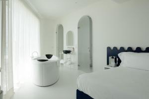 a white bedroom with a white bed and a sink at CALEA Boutique Hotel in Bacoli