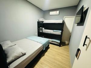グアルーリョスにあるon park hotel e estacionamento trasladoの二段ベッド2台、テレビが備わる小さな客室です。