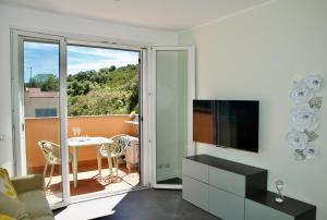 a living room with a television and a table with chairs at Nuovissimo Appartamento Vento d'estate in Castiglione della Pescaia +12 photos