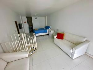 sala de estar con 2 sofás blancos y 1 cama en Angra Inn Praia Grande, en Angra dos Reis