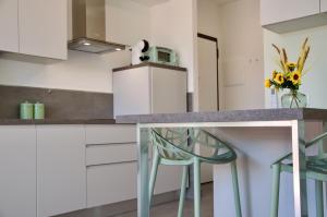 a kitchen with a counter with two chairs and a table at Nuovissimo Appartamento Vento d'estate in Castiglione della Pescaia
