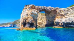 an arch in the water next to a beach at Apervill Luxury House in Apergátika
