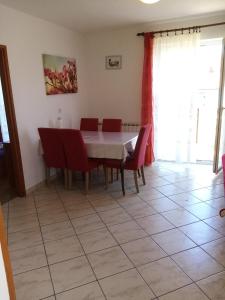 a dining room with a table and red chairs at Apartments Vitkovic in Cres