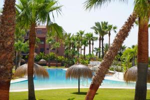 un complexe avec des palmiers et une piscine dans l'établissement Playa Granada Apartamentos Moriscos II, à Motril