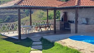 Un cenador con mesa y parrilla y una cocina. en Rancho do Carlinhos, en Ipoema