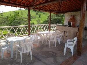 un patio con mesas y sillas blancas y una cocina. en Rancho do Carlinhos, en Ipoema