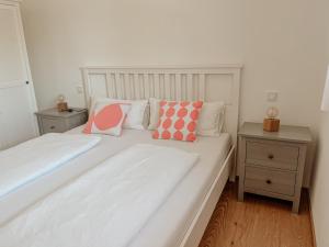 a white bed with pink and white pillows on it at Ferienwohnungen Maria Maier in Gstadt am Chiemsee
