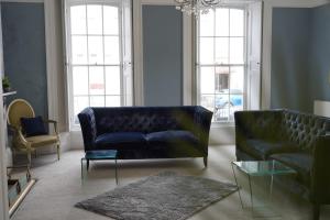a living room with a blue couch and two chairs at THE HOE, BEAUTIFUL 5-BEDROOM HOUSE, GARDEN, SECURE PARKING, SLEEPs 12 in Plymouth