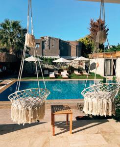 two hanging chairs and a table next to a pool at Limon Hotel in Çeşme