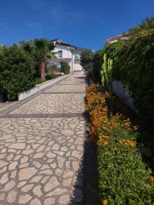 a stone pathway with flowers and a house in the background at Borgo Manfria in Gela