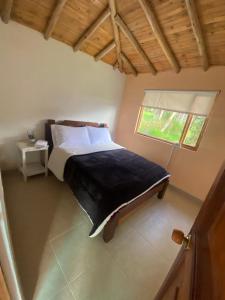 um quarto com uma cama e uma janela em Rancho New Life Guatavita em Guatavita