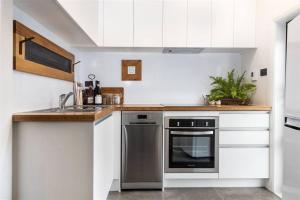 a kitchen with white cabinets and a stainless steel oven at Apartment 1 - Haddin Court - Executive One Bedroom in Blenheim