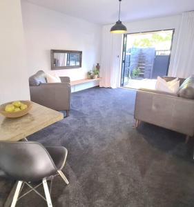 a living room with two couches and a table and a table at Apartment 1 - Haddin Court - Executive One Bedroom in Blenheim