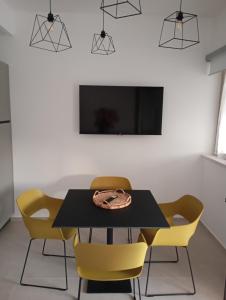comedor con mesa negra y sillas amarillas en Aura Apartments, en Mattinata