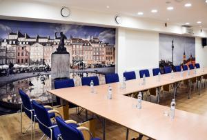 una sala de conferencias con mesas y sillas y un gran mural en Hotel Zielonki, en Zielonki