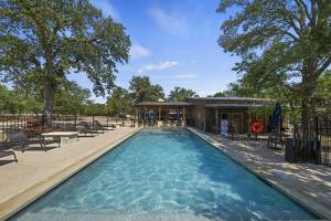a swimming pool at a resort with chairs and trees at Terracotta Bliss Wimberley Retreat For 28 Guests in Wimberley