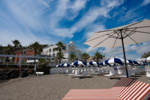 a beach with a bunch of chairs and an umbrella at CALEA Boutique Hotel in Bacoli