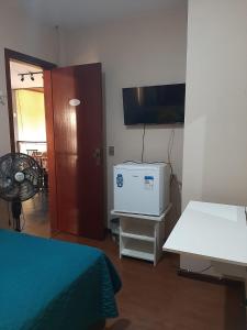 彼得罗波利斯Village Hostel的有一张床、一张书桌和一台电视的房间