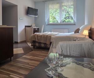una habitación con 2 camas y una mesa con copas de vino en Willa Jagiellonka apartamenty w centrum, parking, en Zakopane