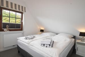 a bedroom with a white bed with towels on it at Rüm Hart II, Weestersir in Hörnum