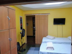 a room with two beds and a flat screen tv at Village Hostel in Petrópolis