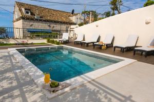 a swimming pool on a patio with chairs and a house at Back in Time Luxury Dubrovnik 2 in Dubrovnik