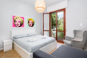 a white bedroom with a bed and a chair at Incantevole e moderno bilocale a soli 500 mt dalle spiagge in Finale Ligure