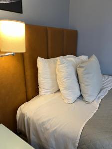 Una cama con cuatro almohadas junto a una lámpara. en Suite 505 Wynd Berrini WTC - SP en São Paulo