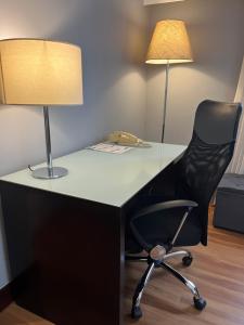 a desk with a black chair and a lamp at Suite 505 Wynd Berrini WTC - SP in Sao Paulo