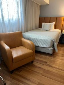 um quarto de hotel com uma cama e uma cadeira em Suite 505 Wynd Berrini WTC - SP em São Paulo