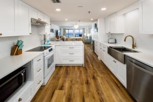 uma cozinha com armários brancos e pisos em madeira em Surf Dweller 406 condo em Fort Walton Beach