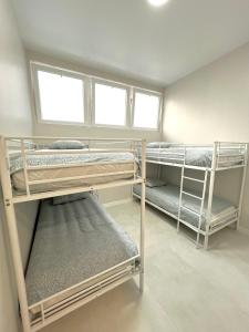 a room with three bunk beds and two windows at Hostel OASIS in Madrid