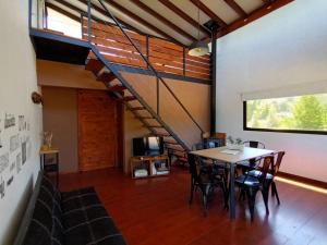 a dining room with a table and a staircase at Cabañas Abedul in Lago Meliquina