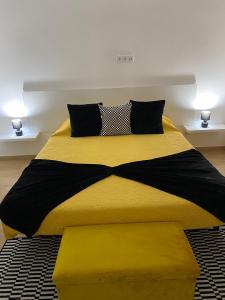 uma cama com um edredom amarelo e preto em O Infinito em Calhetas