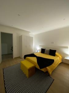 um quarto com uma cama com um cobertor amarelo e um banco em O Infinito em Calhetas mais 4 fotografias