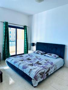 a bedroom with a bed with a blue bedspread and a window at Lux Living Room in Ajman 