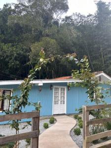 a blue house with a fence in front of it at Morada encanto da cachoeira in Aguas Mornas