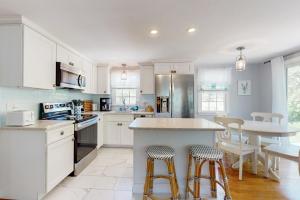 a kitchen with white cabinets and a table with stools at Far Away by the Sea in Yarmouth +13 photos