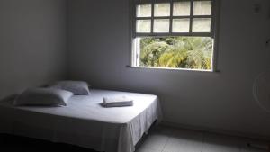 a bed in a white room with a window at Hotel Colonial in Cajati