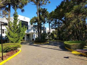 a driveway in front of a white building with trees at Luxuoso Flat no Laje de Pedra -Mountain Village in Canela