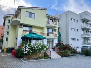 a building with an umbrella and flowers in front of it at Casa Servus Junior in Mamaia Nord