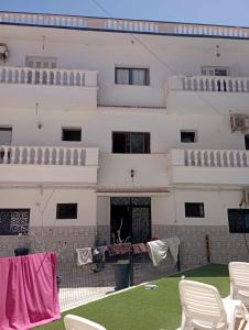 a large white building with chairs in front of it at Le petit VIP in 'Aïn el Turk