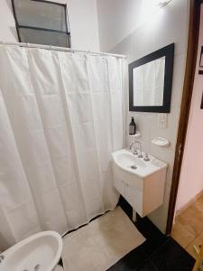 a bathroom with a white shower curtain and a sink at HOSPEJADE ESQUINA in Esquina