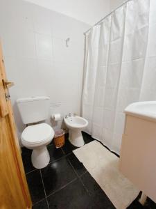 a white bathroom with a toilet and a sink at HOSPEJADE ESQUINA in Esquina