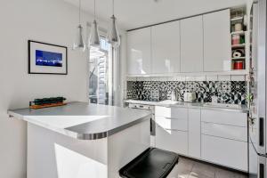 eine weiße Küche mit weißen Schränken und einem schwarzen Stuhl in der Unterkunft Duplex 3 chambres grande terrasse dernier étage in Nanterre + 4 Fotos