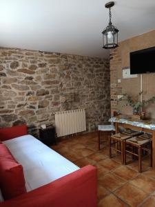 a living room with a red couch and a stone wall at Carroceu Rural in Cangas de Onís +71 photos