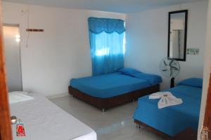 una camera con due letti e una finestra con tende blu di La Guaca a Villavieja Altre 13 foto