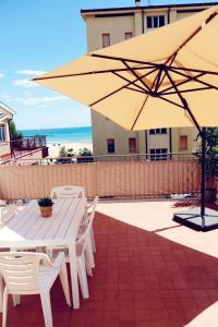 eine Terrasse mit einem Tisch und einem großen Sonnenschirm in der Unterkunft Apartment on the beach in Roseto in Roseto degli Abruzzi