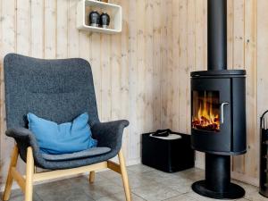 une chaise avec un oreiller bleu à côté d'une cheminée dans l'établissement 10 person holiday home in Storvorde, à Egense