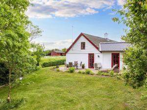 ein weißes Haus mit roten Fenstern und einem Hof in der Unterkunft 6 person holiday home in Thisted in Arup